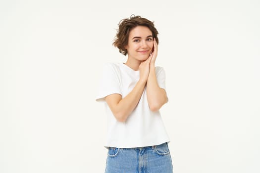 Portrait of cute brunette woman, looking with admiration and excitement, standing over white background.