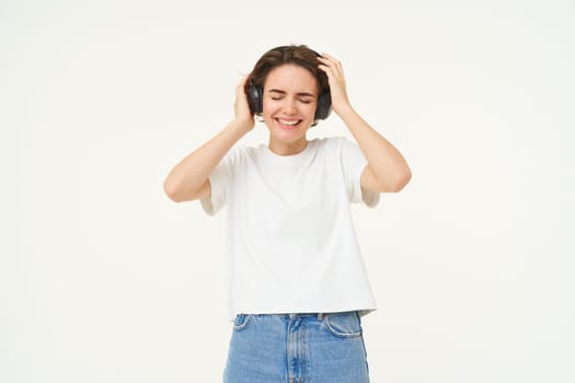 Portrait of smiling young woman, listening to music, enjoying dancing to favourite song, isolated on white background.