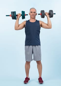 Full body length shot active and sporty senior man lifting dumbbell during weight training workout on isolated background. Healthy active physique and body care lifestyle for pensioner. Clout