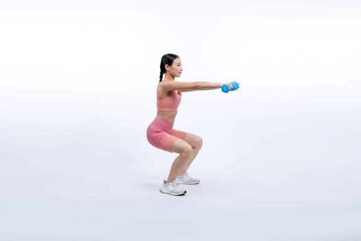 Vigorous energetic woman doing dumbbell weight lifting exercise on isolated background. Young athletic asian woman strength and endurance training session as body workout routine.