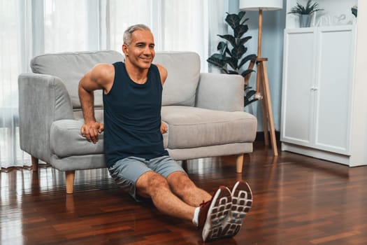 Athletic and active senior man using furniture for effective targeting muscle with push up at home exercise as concept of healthy fit body lifestyle after retirement. Clout