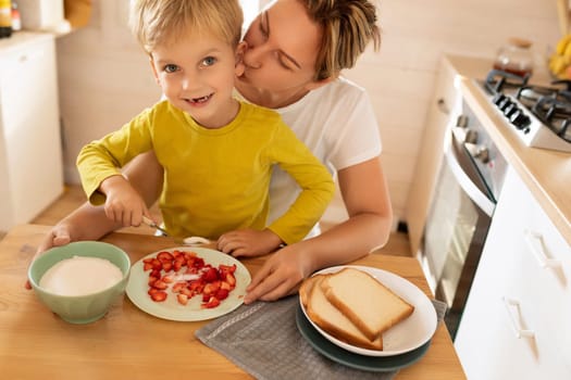 young mother and son sitting at the table and preparing breakfast at home, happy motherhood.