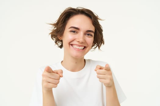 You got this. Happy modern woman, laughing and pointing fingers at you, inviting people, standing over white background.