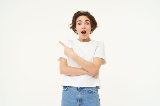Image of excited woman, pointing finger left, showing advertisement, demonstrating brand banner, standing over white background.