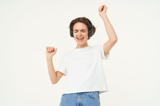 Portrait of smiling young woman, listening to music, enjoying dancing to favourite song, isolated on white background.