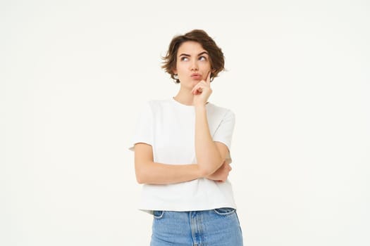 Image of girl thinking, making thoughtful face, making decision, choosing, standing over white studio background.