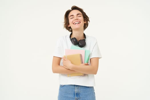 Image of stylish, modern girl student, holding workbook, documents. Woman teacher with papers standing over white background.