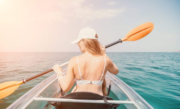 Woman in kayak back view. Happy young woman with long hair floating in transparent kayak on the crystal clear sea. Summer holiday vacation and cheerful female people having fun on the boat.