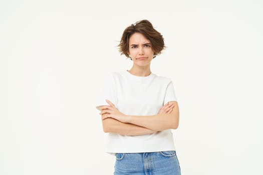 Portrait of dissatisfied woman, cross arms on chest, frowning and pouting, looking unamused, disappointed, standing over white background.