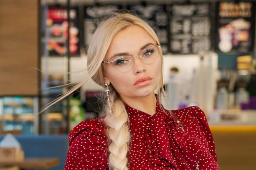 portrait of a beautiful blonde woman in glasses and a red dress
