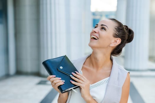 Successful businessman or entrepreneur smiling holding notepad while walking outdoor. City business woman working.