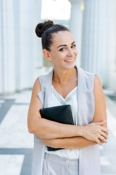 Beautiful woman smiling happy standing at city. Notepad in hand standing on street, in stylish clothes