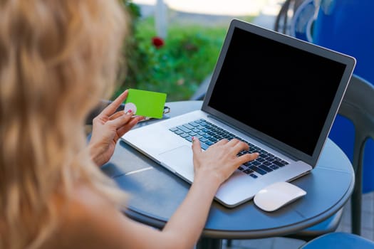 Female entrepreneur working on computer in cafe, doing online shopping with credit card in hand