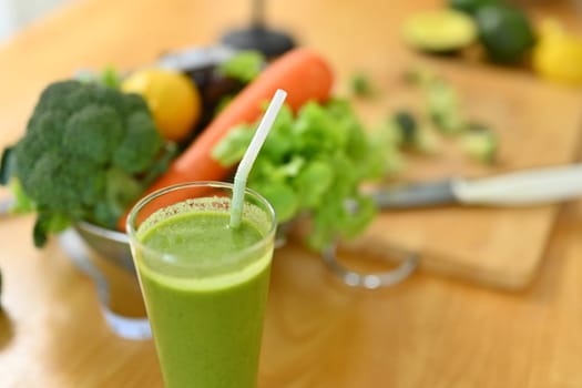 Healthy green smoothie with ingredients on wooden kitchen countertop. Dieting and healthy food concept.