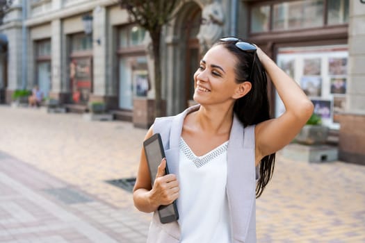 Beautiful woman smiling happy standing at city. Notepad in hand standing on street, in stylish clothes