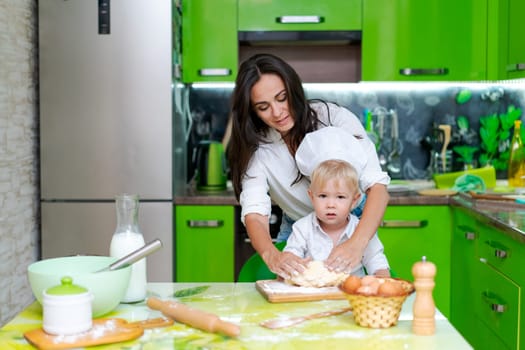 happy mother and son in the kitchen and making dough, family cooking concept