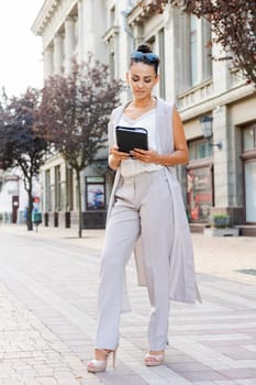 Successful businessman or entrepreneur smiling holding notepad while walking outdoor. City business woman working.