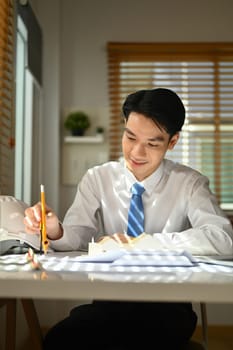 Smiling architect man hand compass to measuring scale on a blueprint. Building, construction and architect concept.