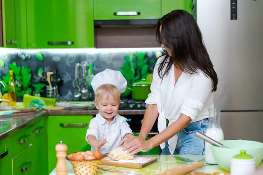 happy mother and son in the kitchen and making dough, family cooking concept