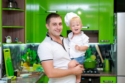 happy family, dad holding son in his arms in the kitchen