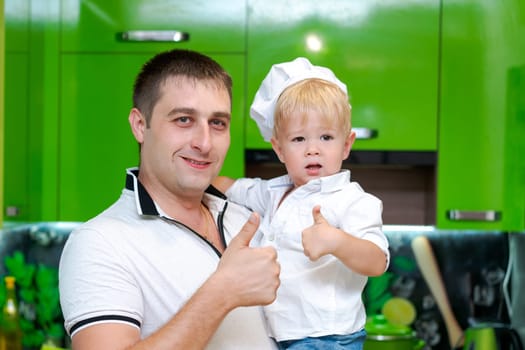 happy family, dad holding son in his arms in the kitchen