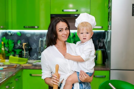 happy family, mother holding her son in her arms in the kitchen