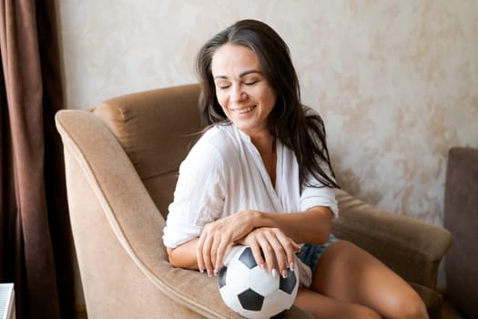 woman sitting on a chair holding a soccer ball in her hand