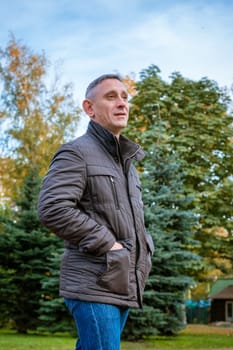 a man in an autumn jacket in the park stands on the path