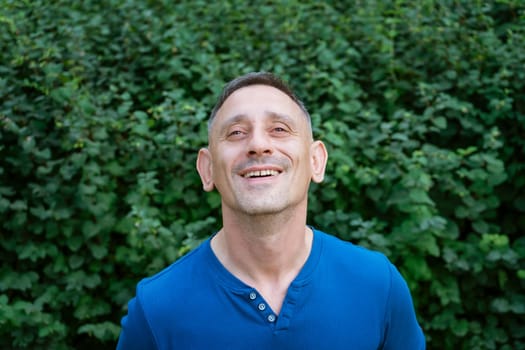 handsome portrait of a man in a blue T-shirt on a park