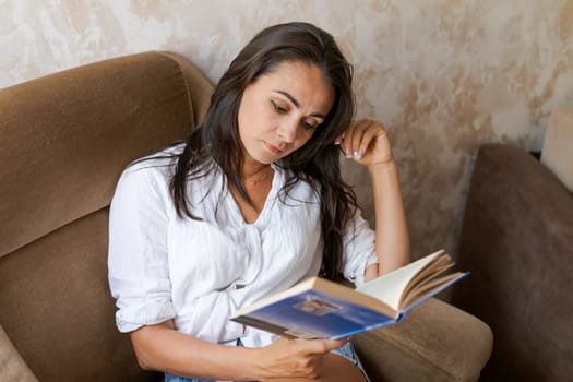 woman sitting on a chair holding a book in her hand, lifestyle concept