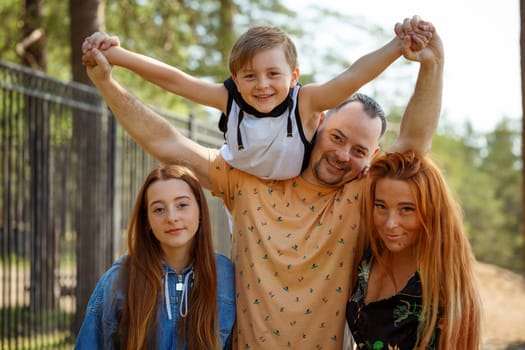 Happy family on a walk in the park, father holds his son in his arms