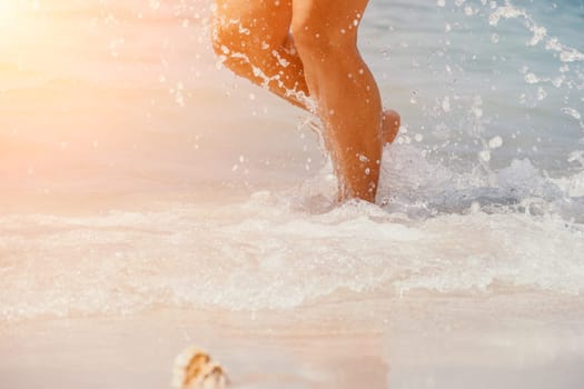 Sea beach travel - woman walking on sand beach leaving footprints in the white sand. Female legs walking along the seaside barefoot, close-up of the tanned legs of a girl coming out of the water