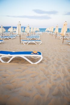 a straw hat rests on a deck-chair near the sea.