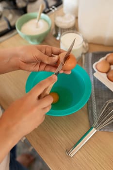 the process of breaking hen's eggs into a bowl, cracked shells.