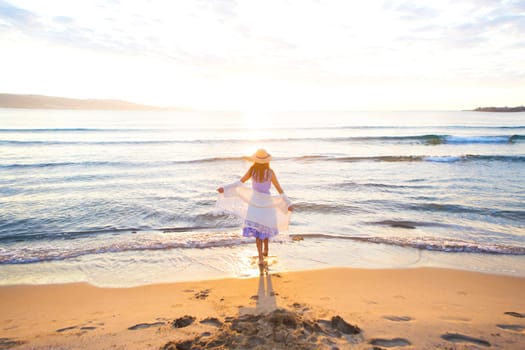 happy beautiful girl in dress and hat runs to meet the sun.