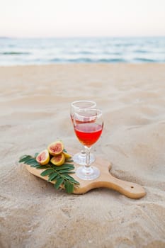 white cape, glasses on a wooden board and sand. Summer picnic close-up.