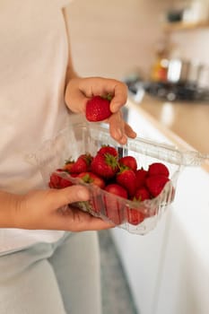 A close-up of farmer's strawberries in a plastic container in the hands of a woman.