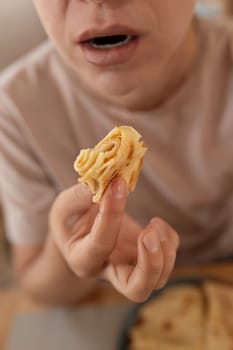 a young woman pulls a piece of pancake into her mouth. concept of gluttony and eating disorder.