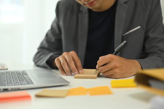 Focused businessman writing down ideas and planning tasks at desk.