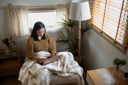 Smiling young woman working remotely on laptop in a minimalist living room.