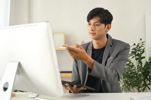 Handsome millennial businessman communicating in an online meeting.
