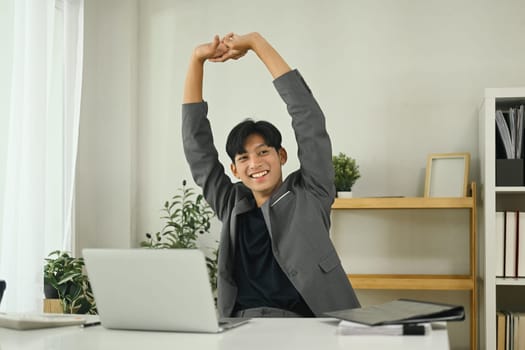 Relaxed office worker stretching after work session in the workplace.