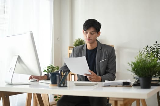Adult businessman in suit analyzing reports in a modern office space.