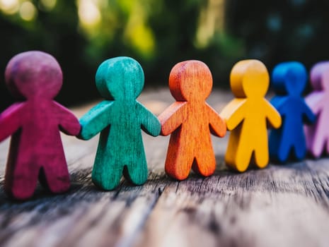 Colorful wooden figures arranged on a table symbolize diversity, unity, and teamwork, reflecting concepts of inclusion and collaboration. Ideal for conveying messages of togetherness and community in a vibrant setting.