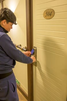 Latin young men opens a door with a keycard in a hallway, key electronic lock, hotel room, holidays in mallorca, spain.