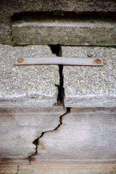 Close-up of a metal staple attempting to repair a large crack in a concrete wall. Highlighting the concepts of damage. Repair