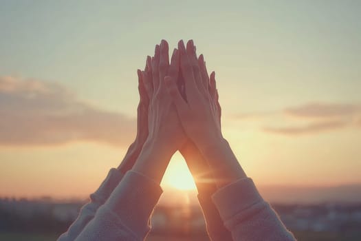 A group of people are holding hands in a pyramid formation, with the sun shining on them. Concept of unity and togetherness, as the people are all connected through their hands