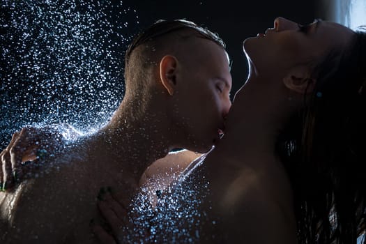 Nude couple embracing in dark shower cropped shot