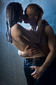 Girl wearing only jeans kissing with a nude man in a shower in the dark