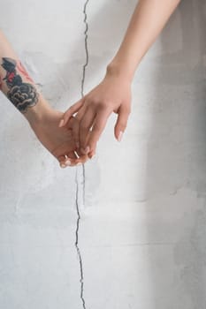Female holding hands cropped shot against cracked wall